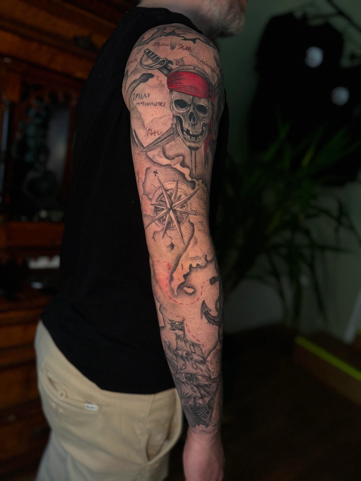 Piraten-Tattoo-Sleeve mit Totenkopf, rotem Kopftuch, Kompassrose, Schatzkarte und Segelschiff
